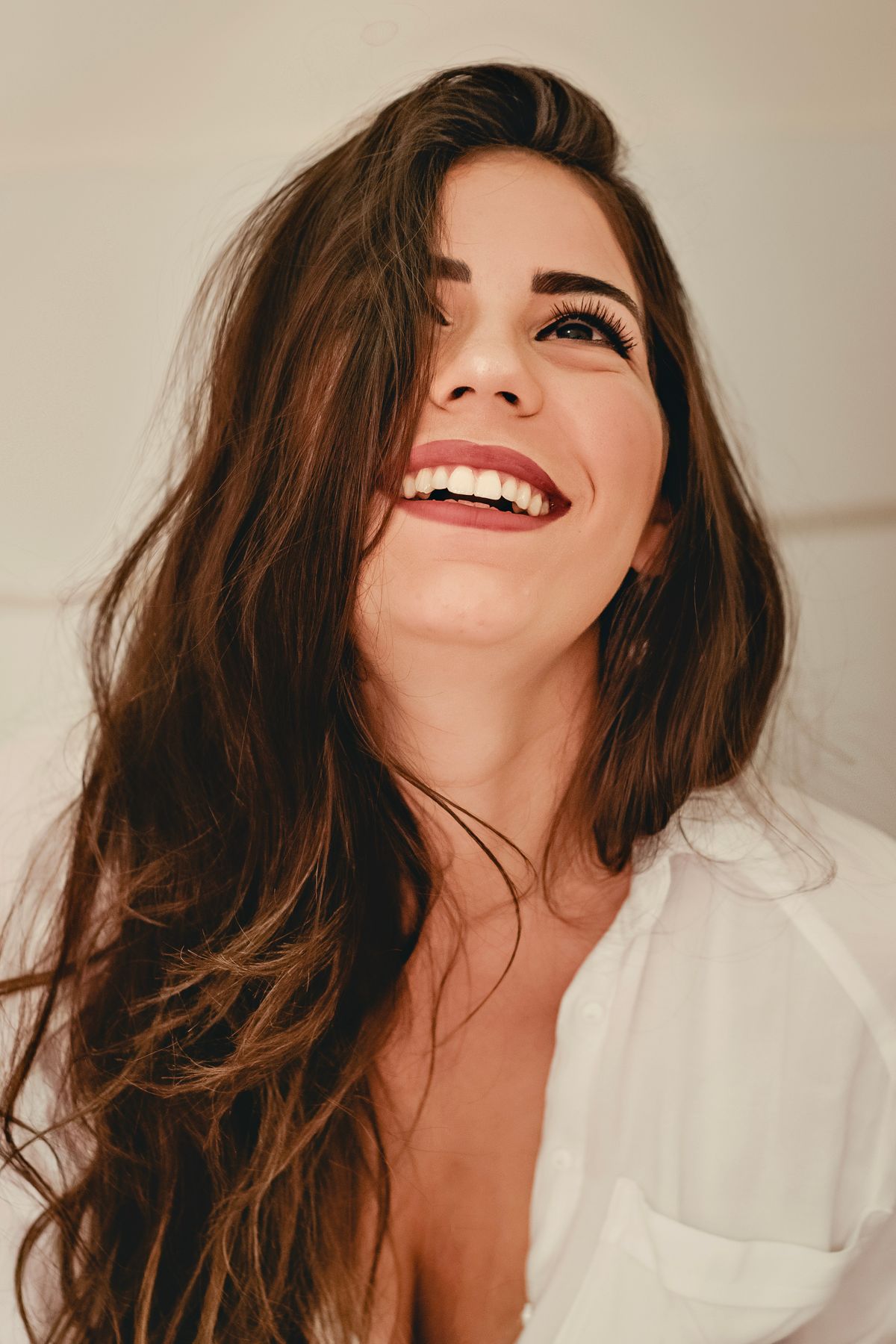 Mulher com sorriso espontâneo em close, em luz natural. Fotografia ilustrativa.