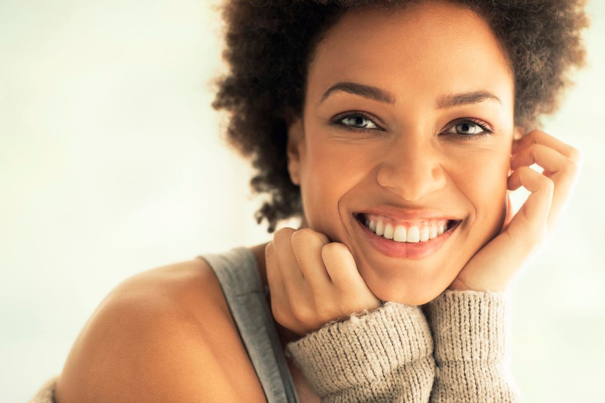 Mulher com sorriso natural e acolhedor em luz suave. Fotografia ilustrativa.